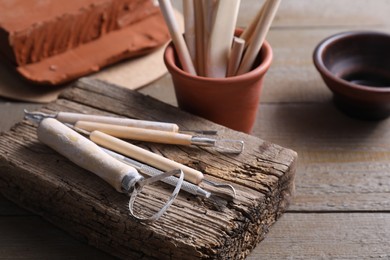 Photo of Set of different clay crafting tools on wooden table, closeup