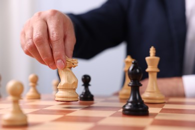 Photo of Man with knight playing chess at checkerboard, closeup