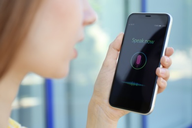 Photo of Woman using voice search on smartphone outdoors, closeup