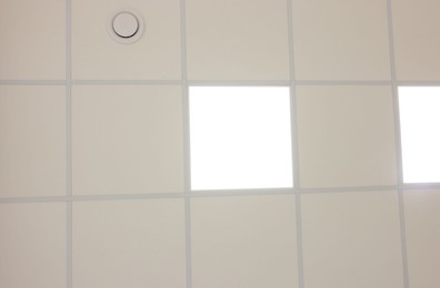 Photo of White ceiling with PVC tiles and lighting, bottom view