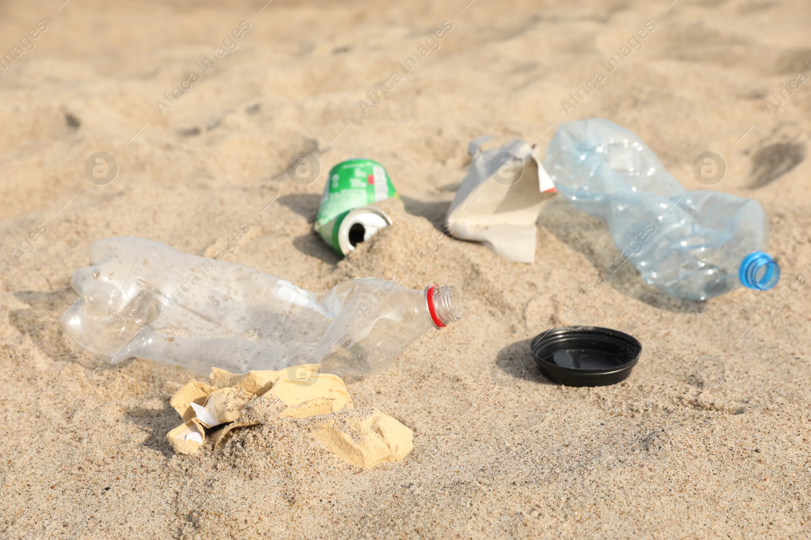 Photo of Different garbage scattered on sand. Recycling problem