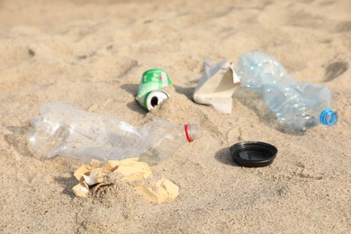 Different garbage scattered on sand. Recycling problem