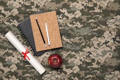 Photo of Diploma, stationery and apple on camouflage background, flat lay with space for text. Military education