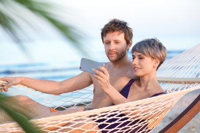 Young couple taking selfie in hammock on beach