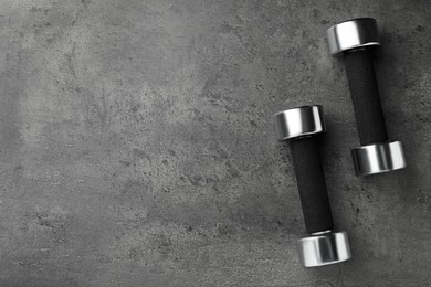 Photo of Dumbbells on grey table, flat lay. Space for text