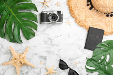 Flat lay composition with professional photographer camera, passport and space for text on white marble table