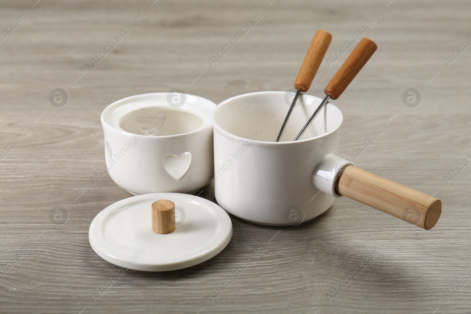 Photo of Fondue set on wooden table. Kitchen equipment