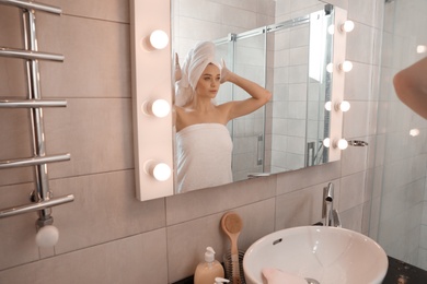 Photo of Young woman wrapped in towels near bathroom mirror. Using soap