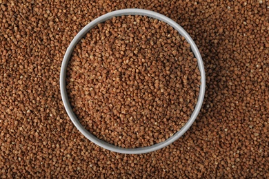 Photo of Uncooked buckwheat in bowl on grains, top view