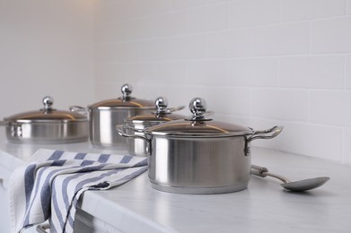 Photo of Set of new clean cookware and spoon on countertop in kitchen