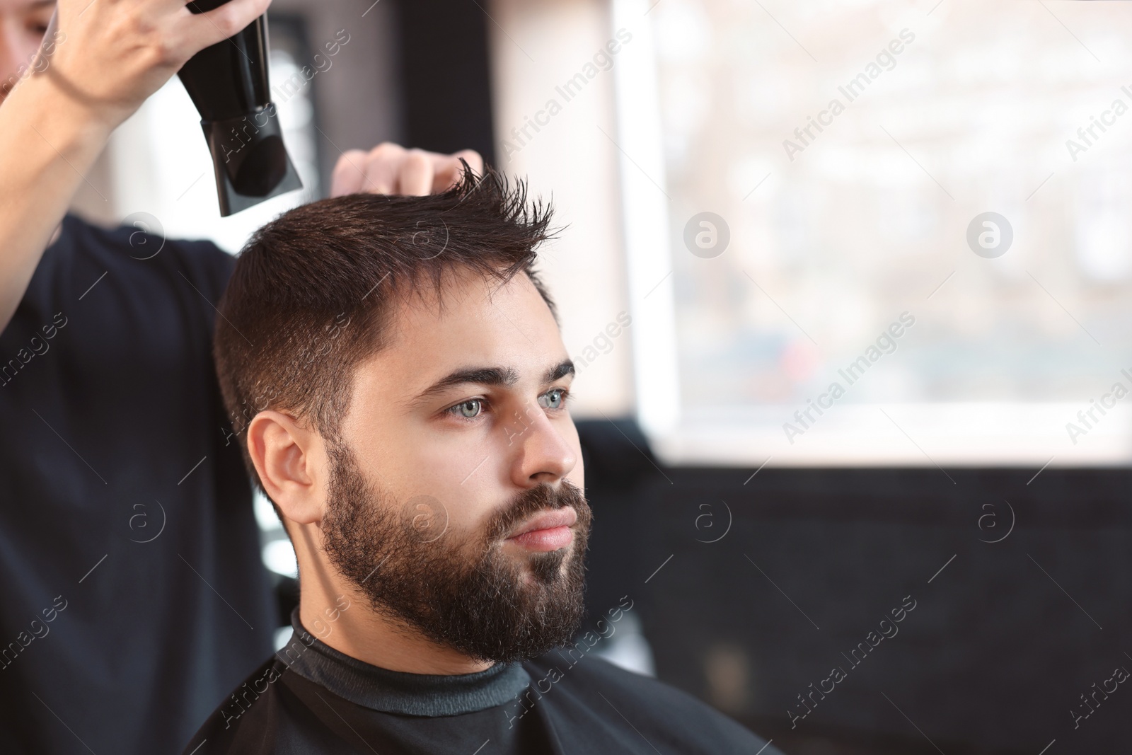 Photo of Professional hairdresser working with client in barbershop