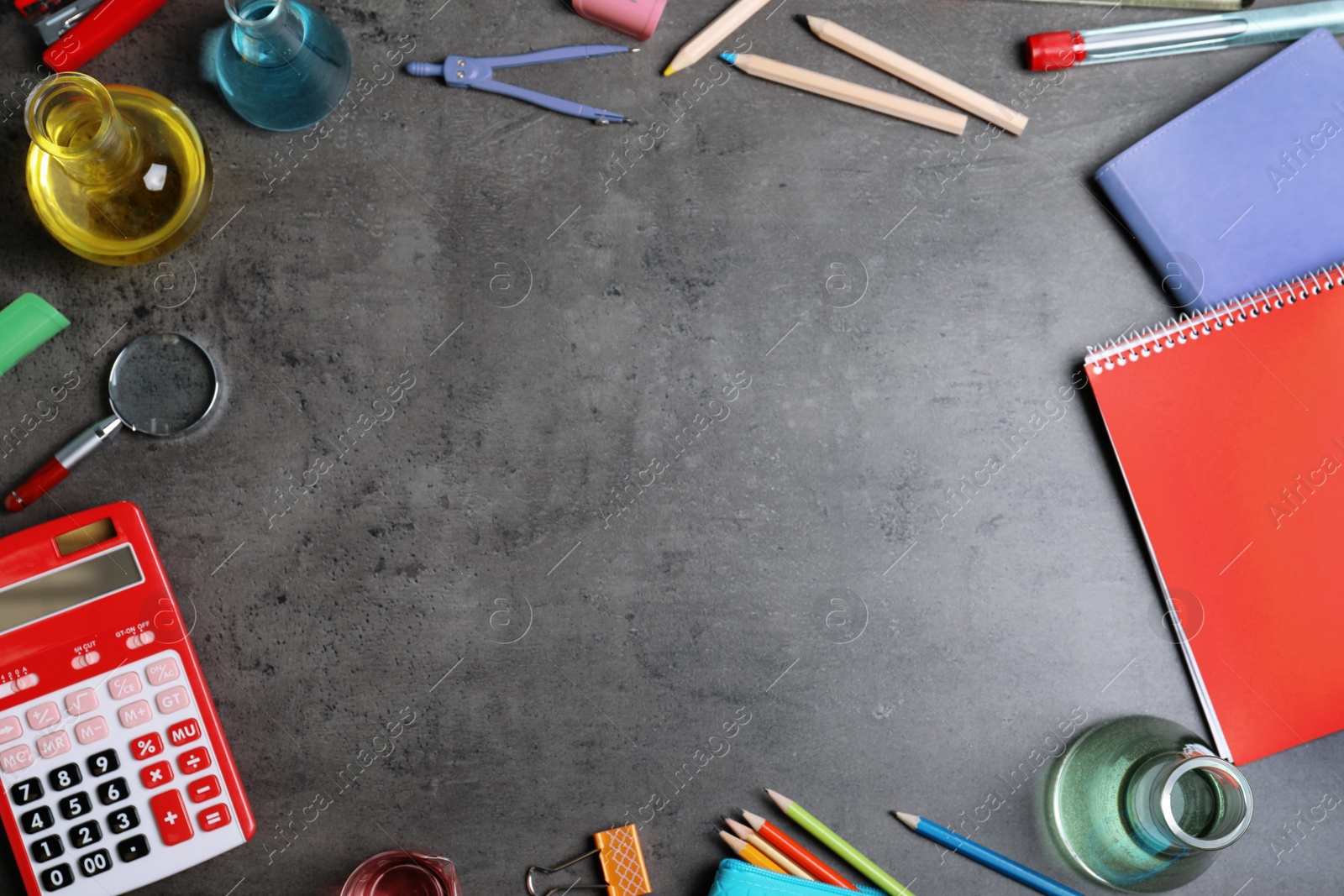 Photo of Laboratory glassware and school supplies on grey background, top view with space for text