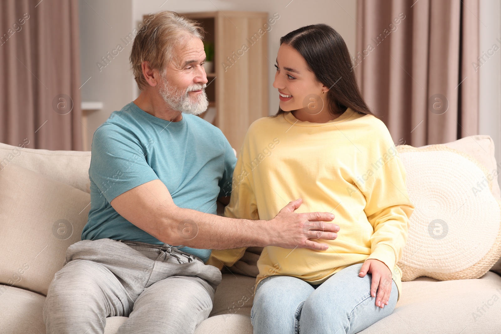 Photo of Happy pregnant woman spending time with her father at home. Grandparents' reaction to future grandson