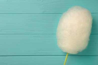 Photo of One sweet cotton candy on turquoise wooden table, top view. Space for text