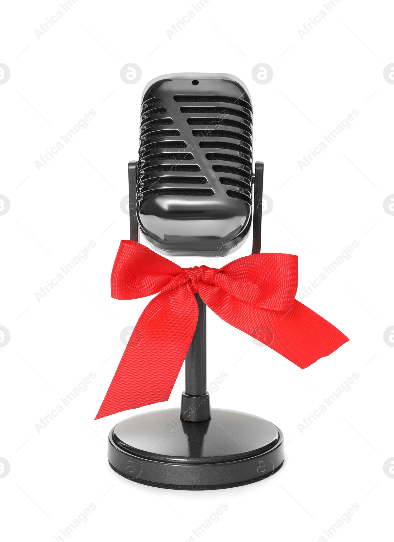 Photo of Retro microphone with red bow isolated on white. Christmas music