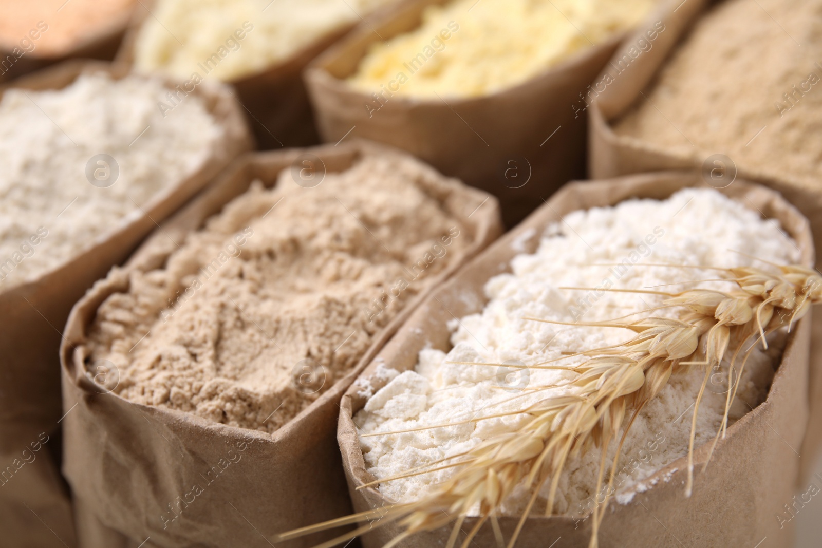 Photo of Paper sacks with different types of flour as background, closeup