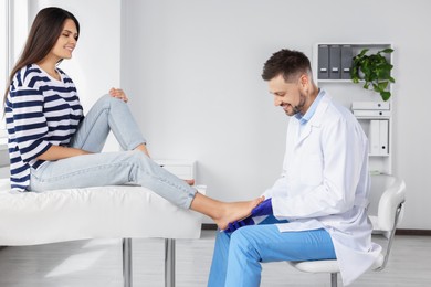 Male orthopedist fitting insole to patient's foot in hospital