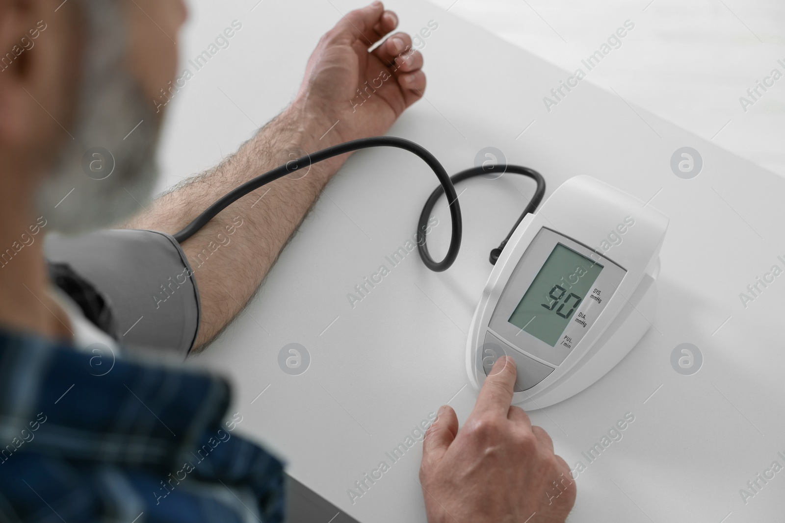 Photo of Man measuring blood pressure at table indoors, closeup