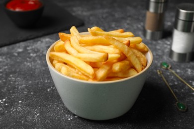 Photo of Delicious fresh french fries in bowl on black table, closeup