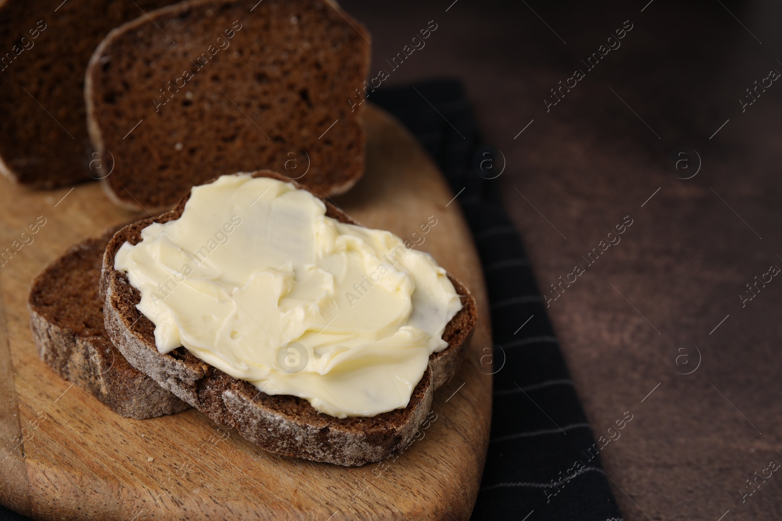 Photo of Slices of tasty bread with butter on grey textured table, closeup. Space for text