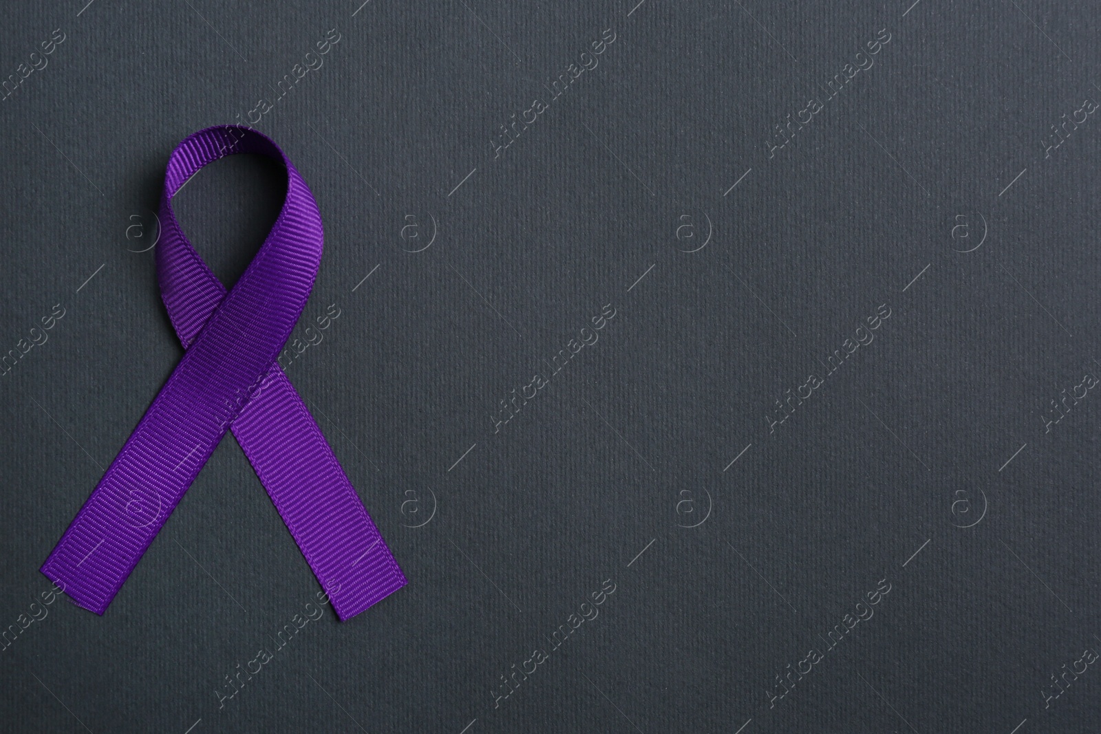 Photo of Purple awareness ribbon on black background, top view with space for text