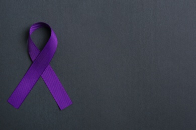 Purple awareness ribbon on black background, top view with space for text