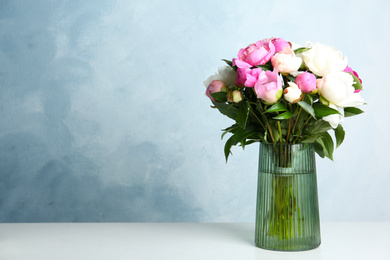 Photo of Bouquet of beautiful peonies in vase on white table. Space for text