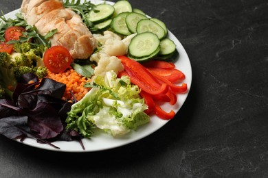 Photo of Balanced diet and healthy foods. Plate with different delicious products on black table, closeup. Space for text