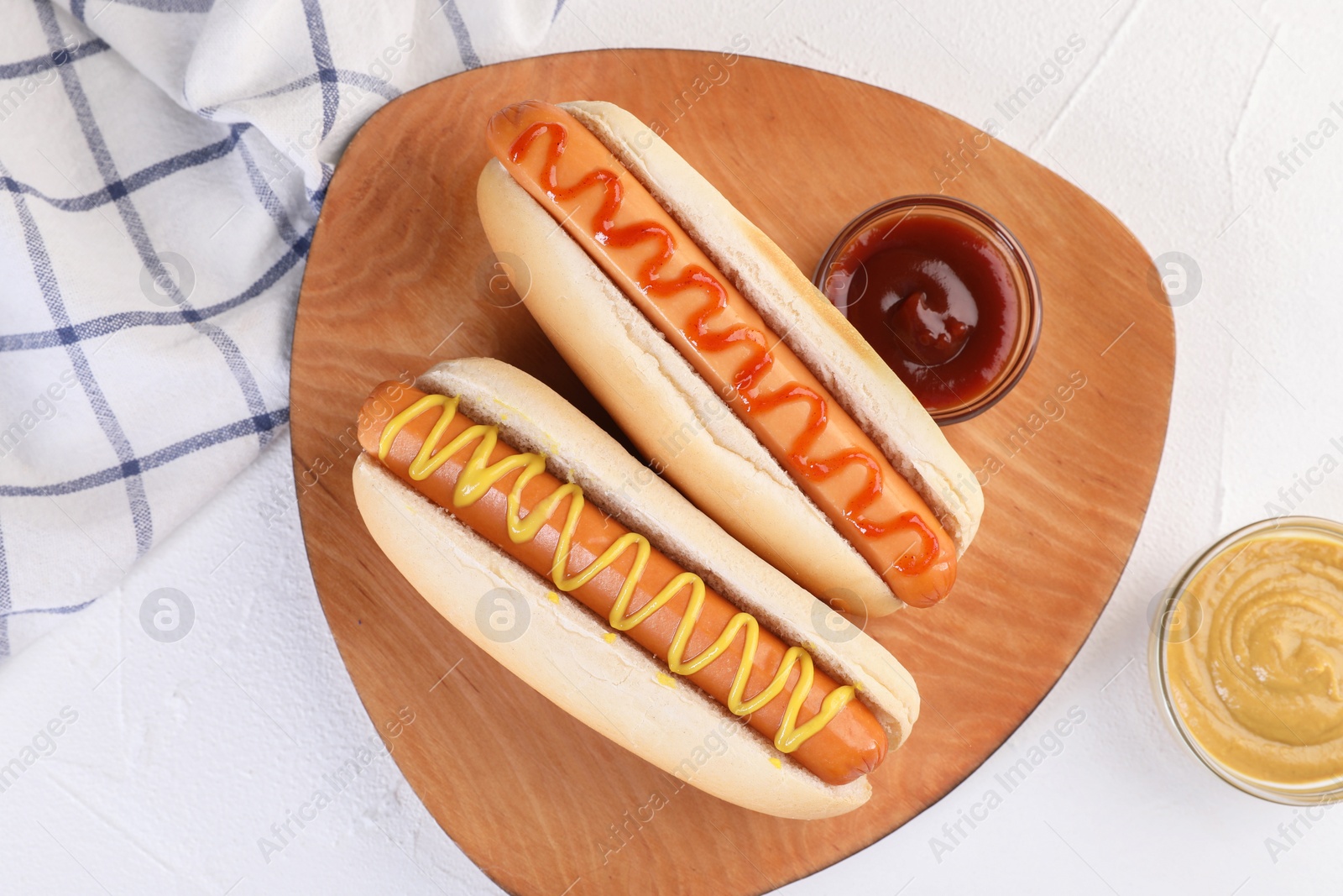 Photo of Tasty hot dogs with ketchup and mustard on white table, flat lay