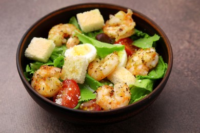 Photo of Delicious Caesar salad with shrimps on brown table, closeup