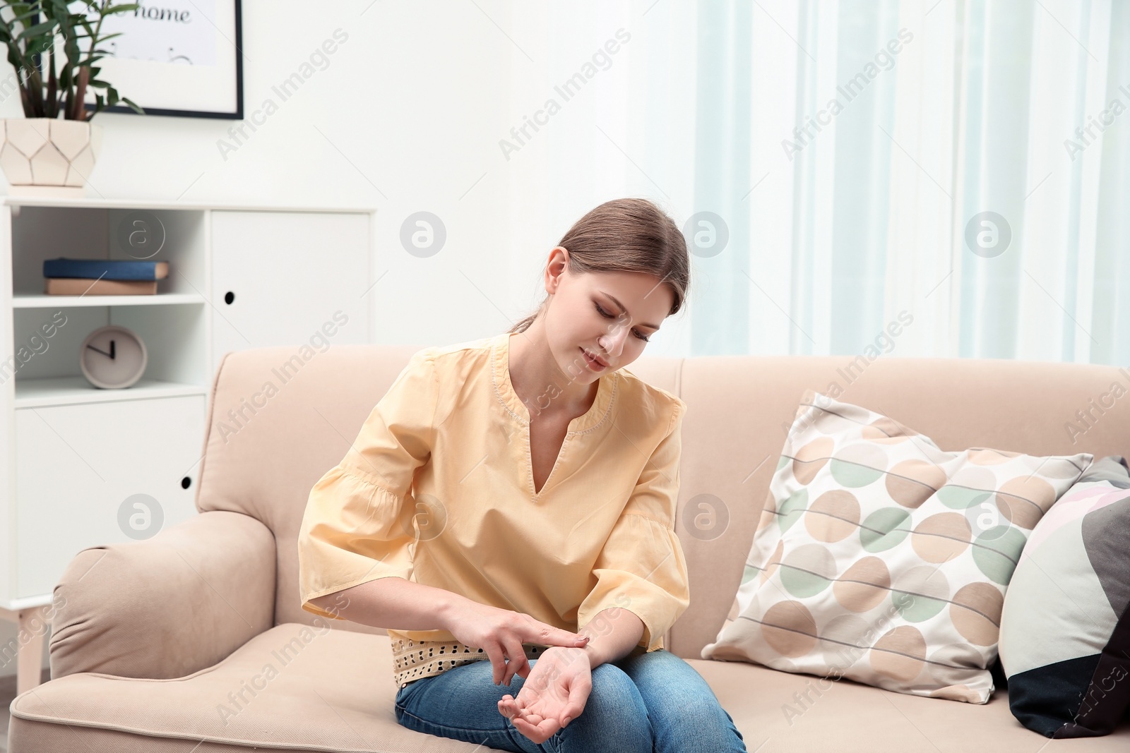 Photo of Young woman checking pulse in living room