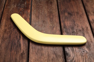 Photo of Yellow boomerang on wooden background. Outdoors activity