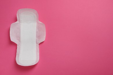 Photo of Sanitary napkin on pink background, top view. Space for text