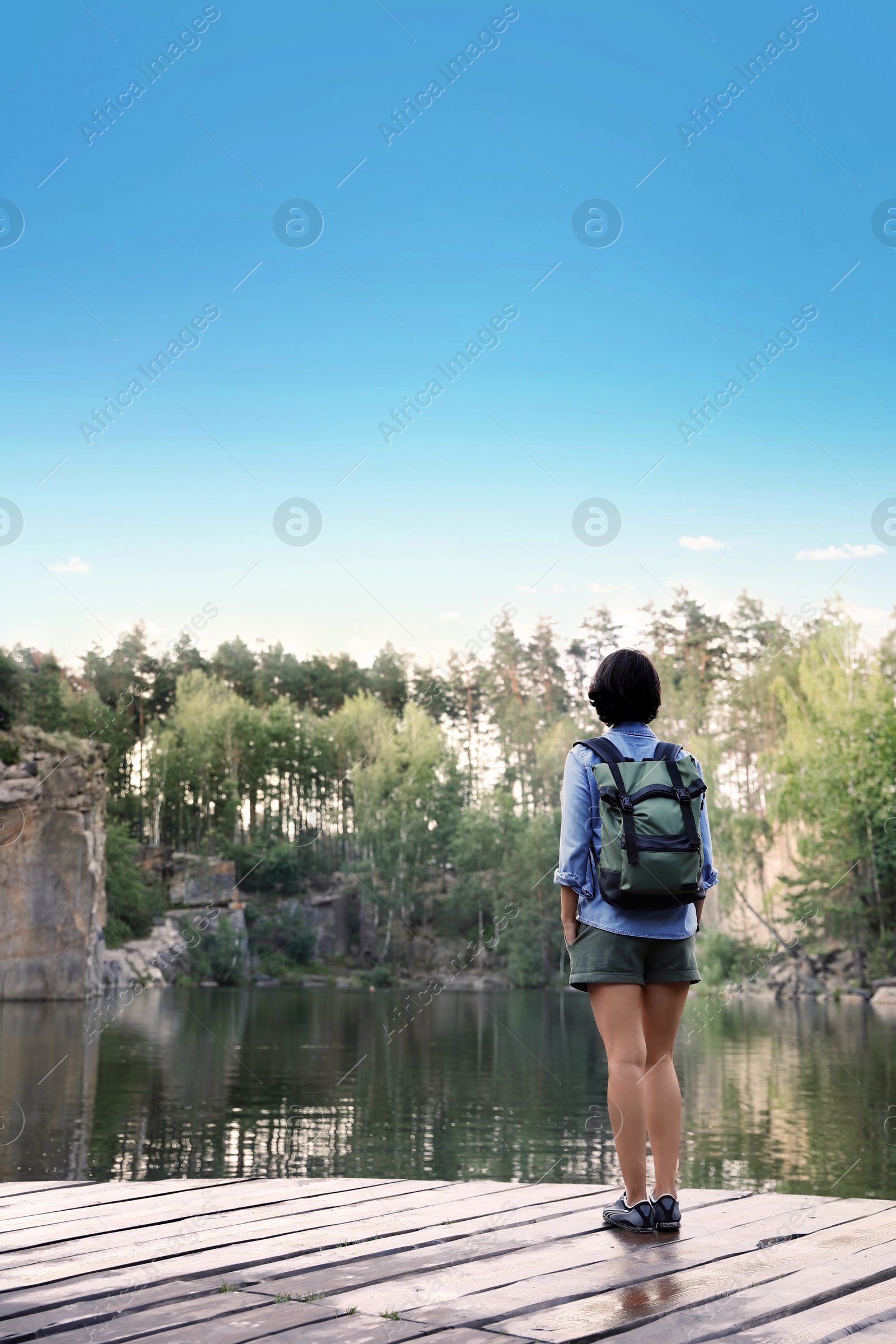 Photo of Young woman on wooden pier near lake. Camping season