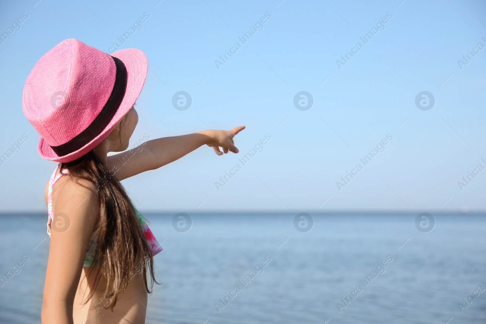 Photo of Cute little child pointing at something in sky. Beach holiday
