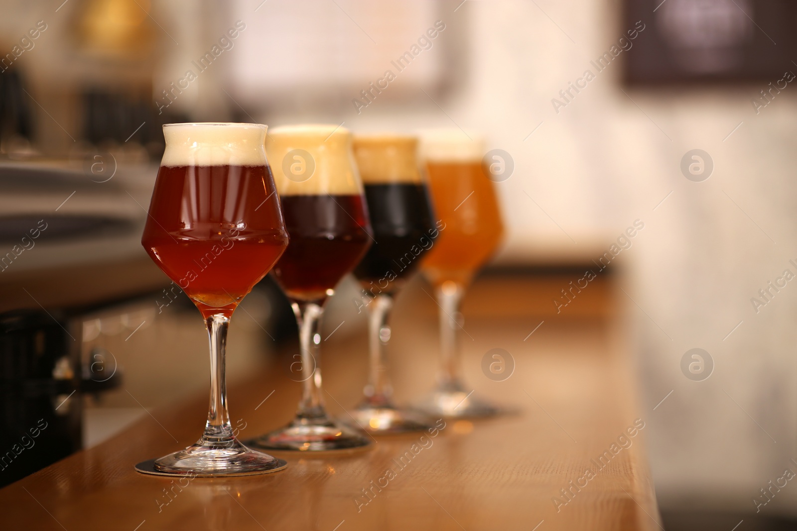 Photo of Different beers in glasses on bar counter, space for text