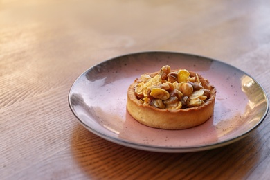 Plate with delicious cake on wooden table