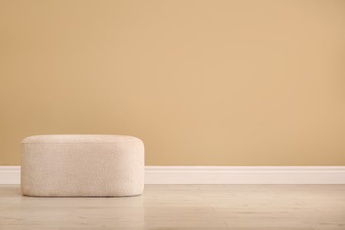 Photo of Stylish comfortable pouf near beige wall indoors, space for text