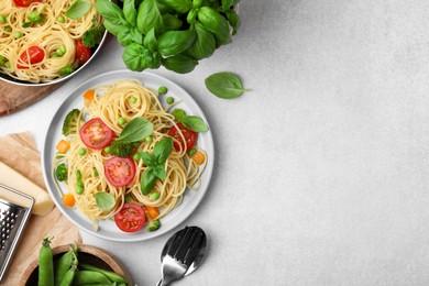 Photo of Delicious pasta primavera and ingredients on light gray table, flat lay. Space for text