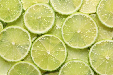 Photo of Juicy lime slices as background, top view. Citrus fruit