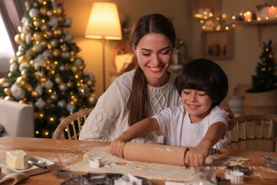 Mother with her cute little son making Christmas cookies in kitchen