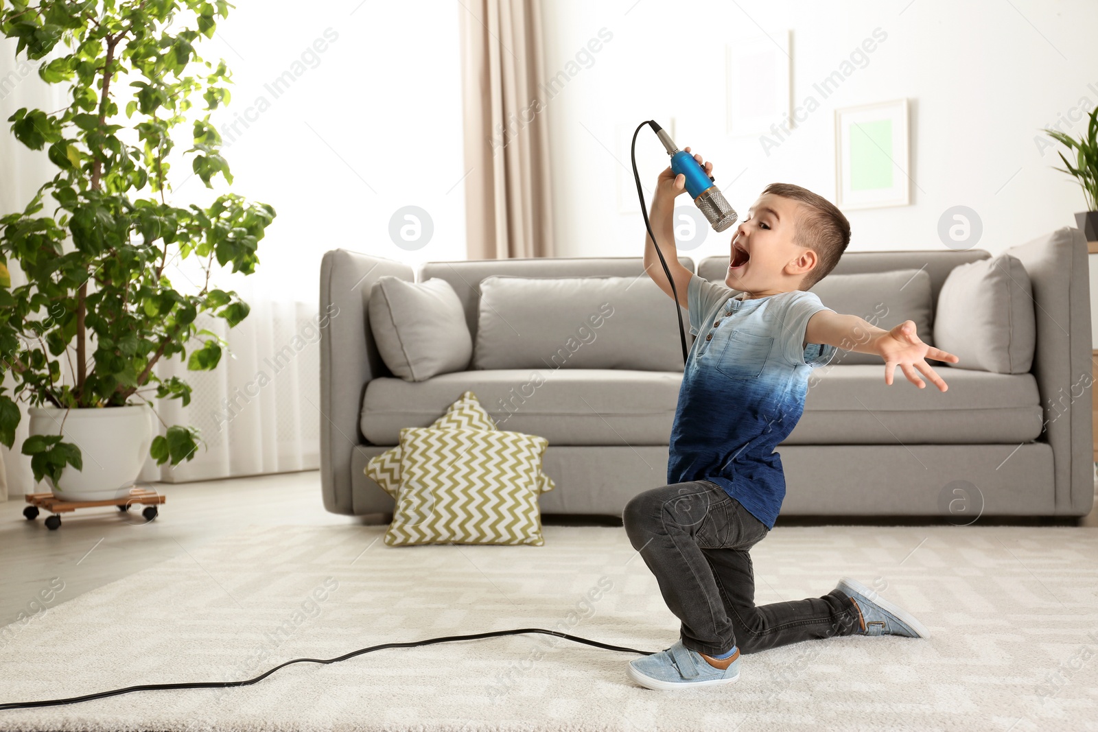 Photo of Cute funny boy with microphone in living room