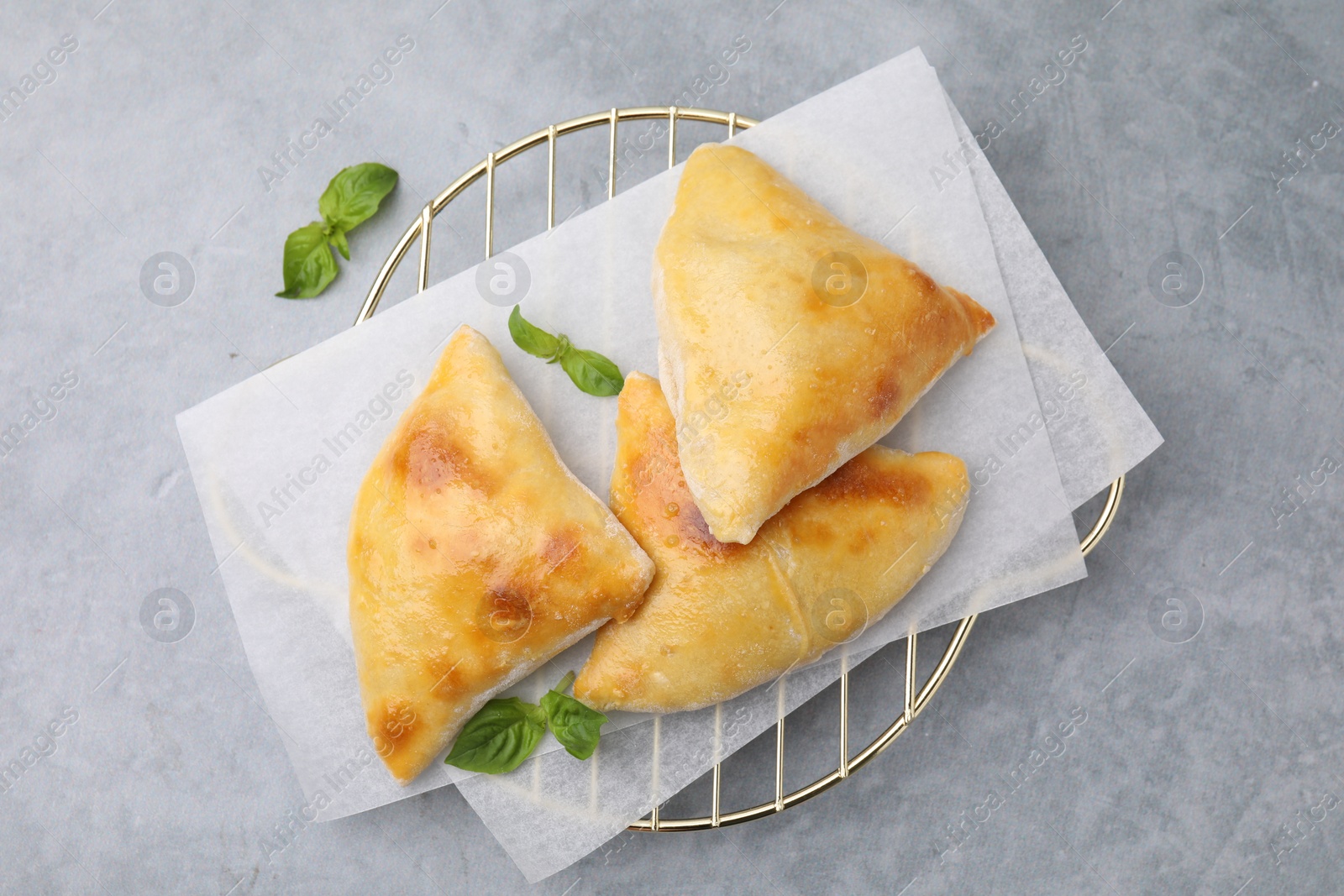 Photo of Delicious samosas and basil on grey table, top view