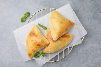 Photo of Delicious samosas and basil on grey table, top view