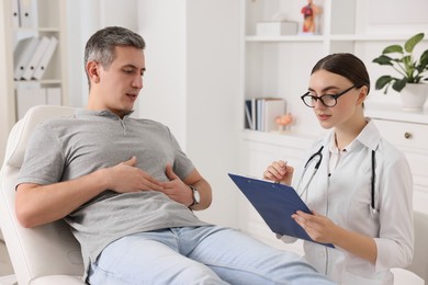 Gastroenterologist with clipboard consulting patient in clinic