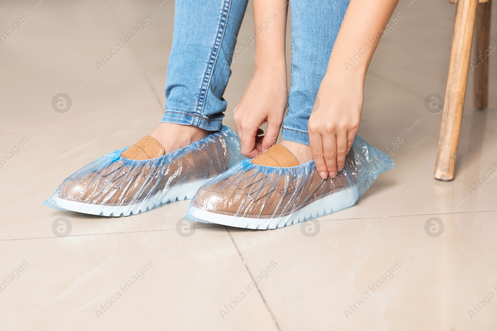 Photo of Woman putting on blue shoe covers, closeup