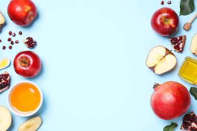 Honey, apples and pomegranates on light blue background, flat lay with space for text. Rosh Hashanah holiday