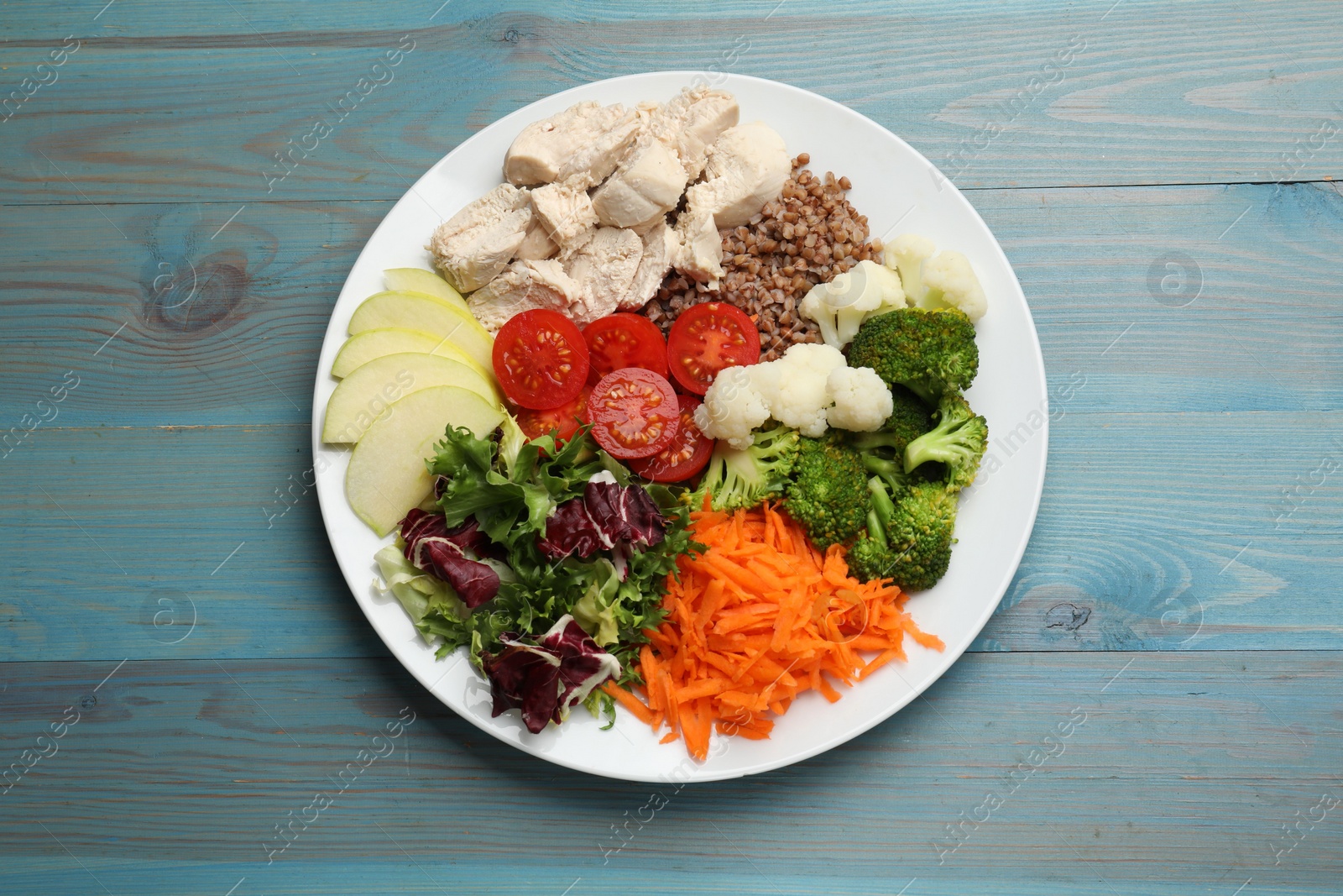 Photo of Balanced diet and healthy foods. Plate with different delicious products on blue wooden table, top view