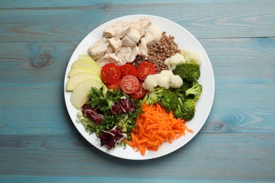 Photo of Balanced diet and healthy foods. Plate with different delicious products on blue wooden table, top view