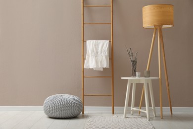 Photo of Stylish room interior with pouf, ladder and decor elements. Space for text